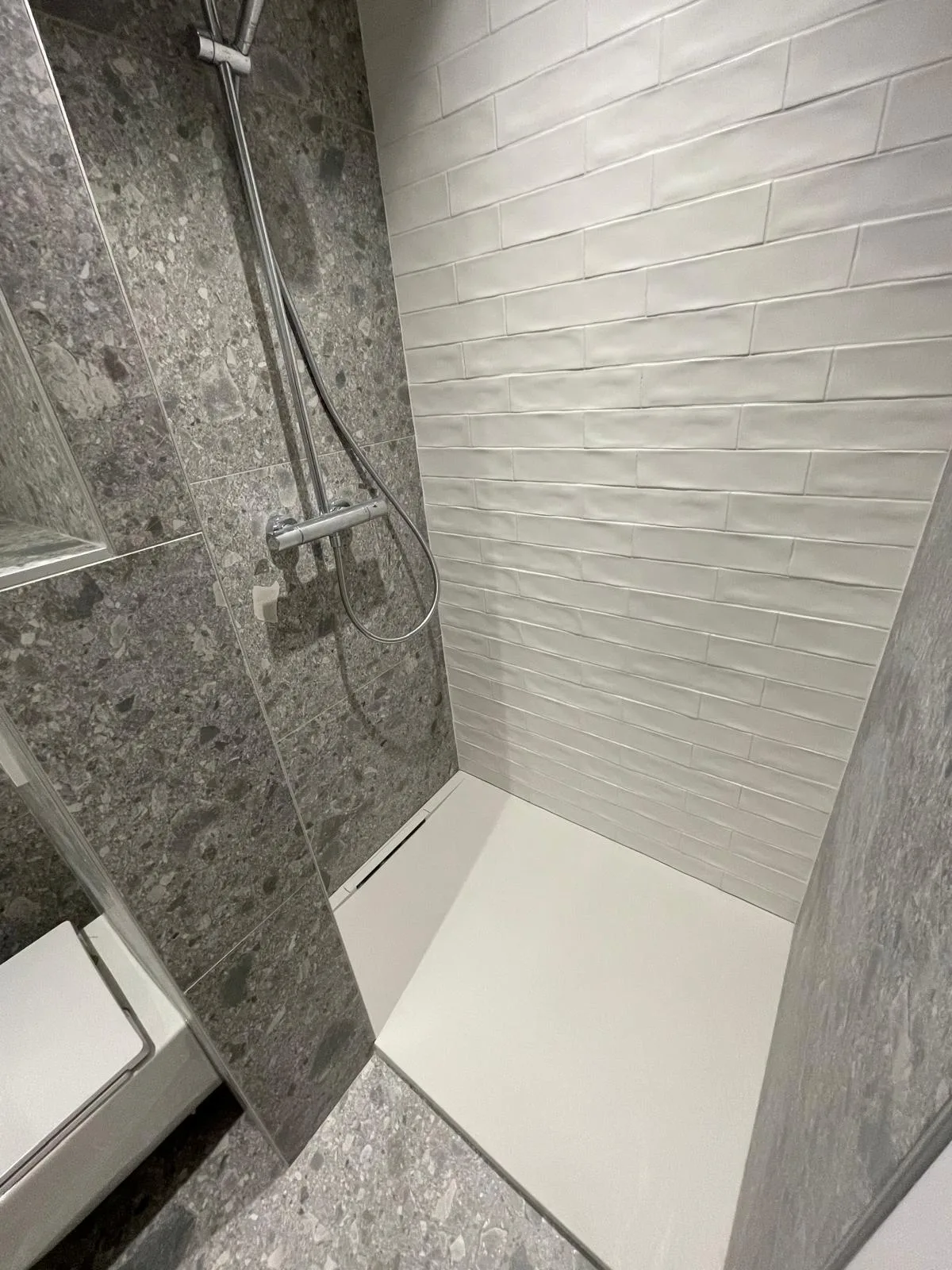 Douche avec mur en carrelage effet pierre gris et faïence blanche