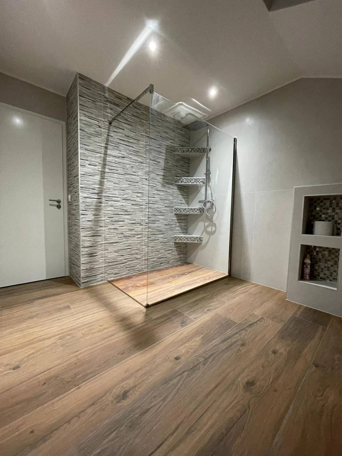 Douche à l’italienne avec paroi vitrée et mur en mosaïque de pierre