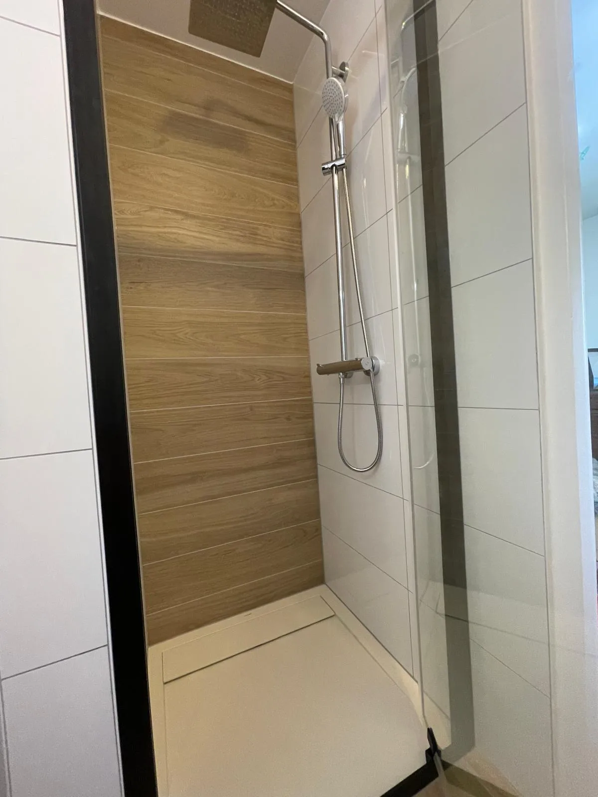 Douche avec mur effet bois et paroi vitrée à profilé noir