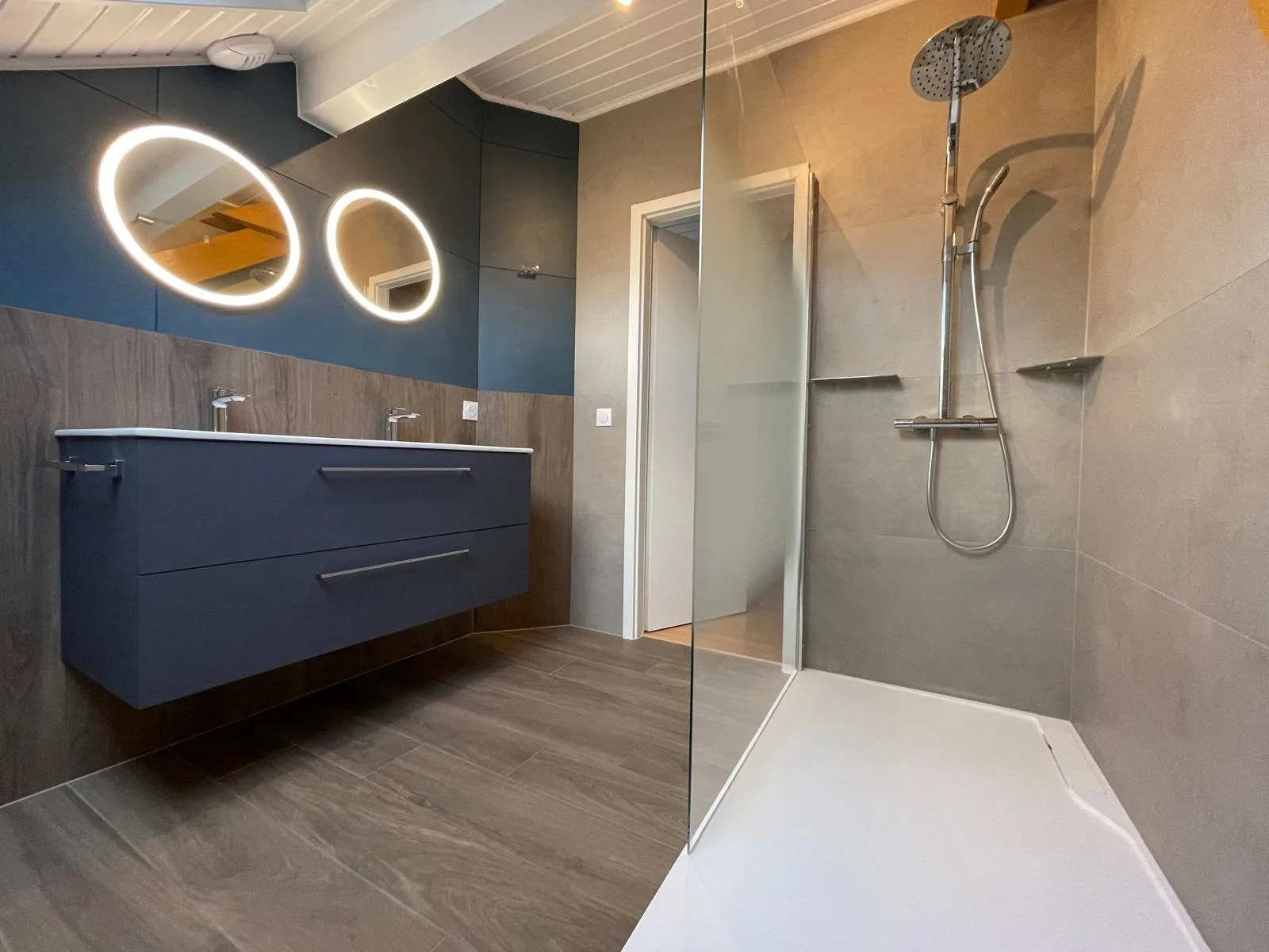 Douche à paroi vitrée face au meuble vasque