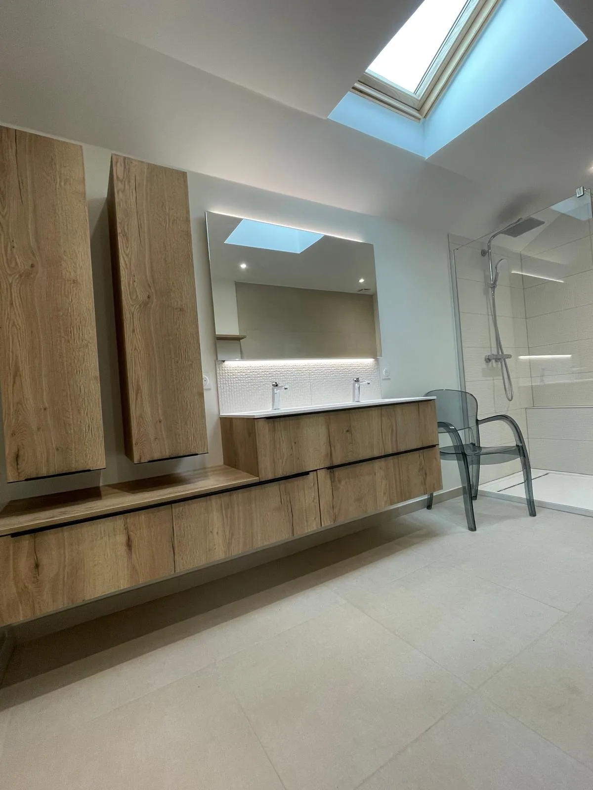 Salle de bains sous velux avec meubles suspendus en bois et miroir rétroéclairé