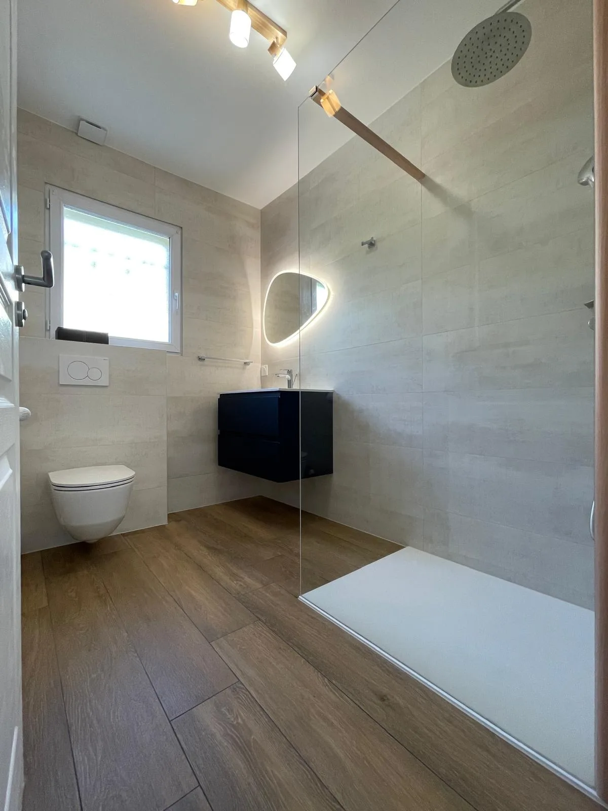Salle de bains avec douche vitrée, WC suspendu et meuble vasque bleu foncé